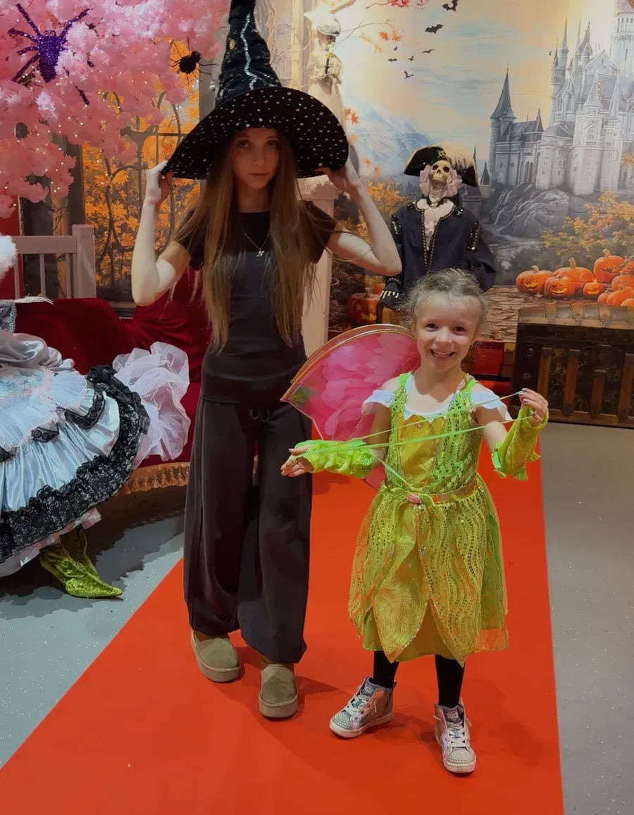 A little fairy and a young witch on the red carpet in front of the enchanted castle