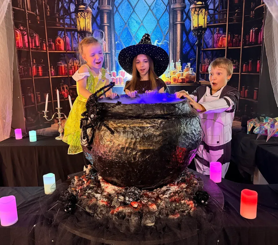 Children gathered around the witch's smoking cauldron at Funtoria